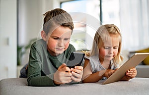 Little girl and boy watching video or playing games on their digital device tablet, smartphone.