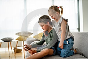 Little girl and boy watching video or playing games on their digital device tablet, smartphone.