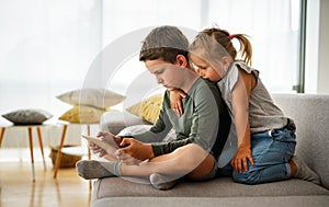 Little girl and boy watching video or playing games on their digital device tablet, smartphone.