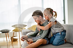 Little girl and boy watching video or playing games on their digital device tablet, smartphone.