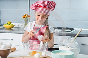 Little girl breaking eggs into bowl