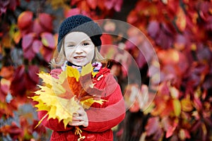 Little girl in bright red coat at autumn