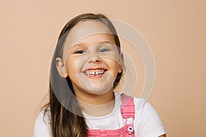 Little girl with bright shining eyes and excited blissful smile with teeth looking at camera wearing bright pink