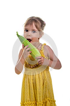 Little girl in a bright yellow dress with ear of corn. Studio photo, bright white background.