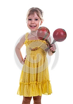 Little girl in a bright yellow dress holding maracas in her hands. Studio photo, bright white background.