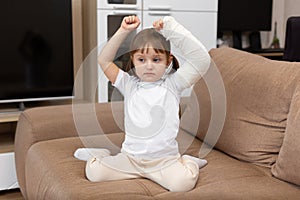 A little girl with a broken arm and a cast raises her arms up