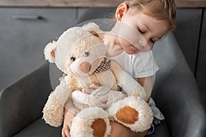 Little girl with broken finger holds teddy bear with a bandaged paw at the doctor& x27;s appointment in the hospital