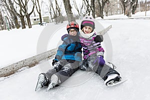 Little girl and brother enjoying ice skating in winter season