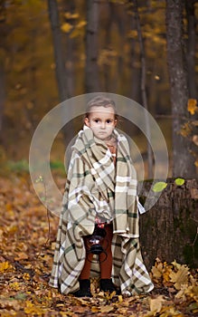 Little girl on a brown coat and warm plaid holds lamp outdoors. Autumn time. Happy child playing at fall nature background. Autumn