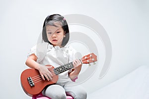 Little girl with brown ukulele toy gift. Child learn to play strum instruments