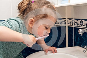 Little girl brushes her teeth in the morning in the bathroom