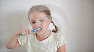 A little girl brushing her teeth with a brightly colored toothbrush