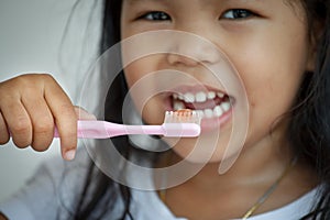 Little girl brushing her teeth close up on toothbrush