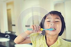 Little girl brushing her teeth isolated on toilet