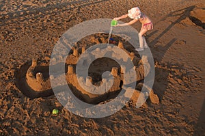 Little girl buiding big sandcastle on a sandy beach