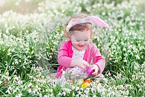 Little girl with bunny ears on Easter egg hunt