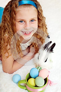 Little girl with a bunny rabbit has a easter at white carpe