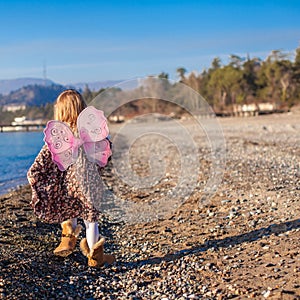 Little girl with butterfly wings running along the