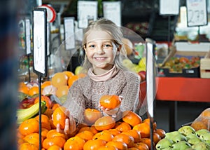 Little girl buying mandarins in shop