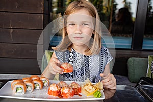 little girl in cafe restaurant eats Asian Philadelphia rolls with great pleasure