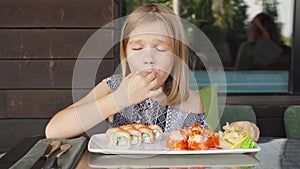 little girl in cafe restaurant eats Asian Philadelphia rolls with great pleasure