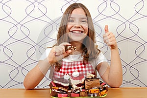 Little girl with cakes and thumb up