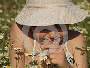 Little girl with a camomile in her hand in the middle of the chamomile field