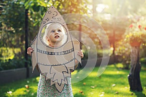 Little girl with cardboard rocket dreaming about flying in space and astronaut profession in future. imagination, freedom and