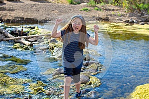 Little girl carefully crossing a stream at a park