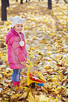 Little girl carries plastic wheelbarrow loaded