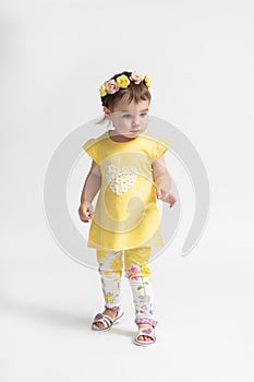 Little girl in a casual children\'s dress with a wreath of flowers on her head