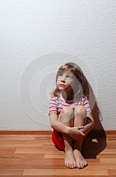 Little girl in casual clothes looks sad to corner