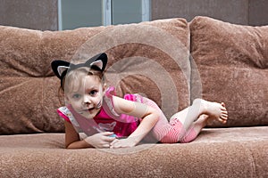 Little girl with cat face painting on couch