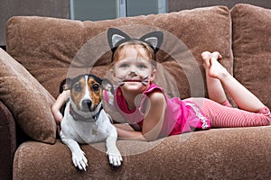 Little girl with cat face painting embrace dog
