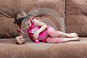 Little girl with cat face painting play ball on couch