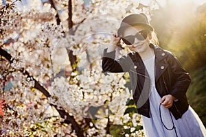 Little girl with a cat hat and black sunglasses in early spring in sunny weather