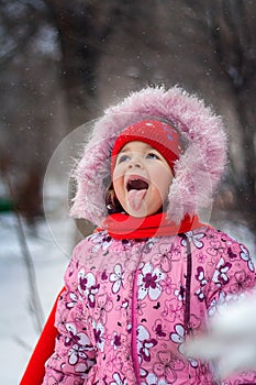 The little girl catches a snowflake mouth on walk in the park