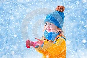 Little girl catching snow flakes