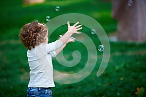 Little girl catching soap bubbles in the park