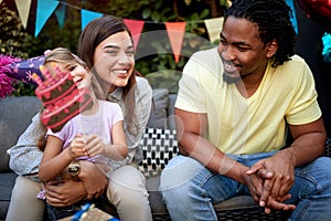 Little girl celebrating birthday with her adult friends and family