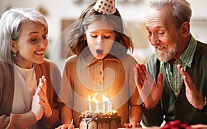 Little girl celebrating birthday while her loving senior grandparents at home