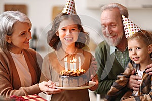 Little girl celebrating birthday while her loving senior grandparents at home