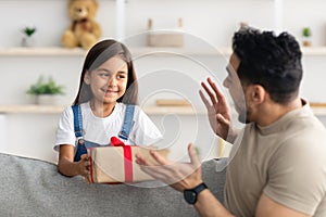 Little girl celebrating father& x27;s day, greeting excited dad with box