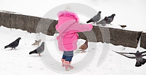 A little girl chasing pigeons in the winter