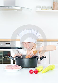 Little girl in chef hat cooking.