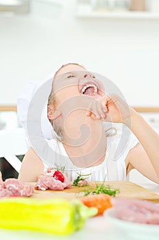 Little girl in chef hat laughing.