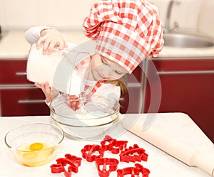 Little girl with chef hat put flour