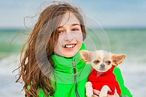 Little girl with chihuahua dog on seashore, outdoor. Girl and chihuahua at the sea. Teenager and dog