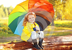 Little girl child with colorful umbrella in sunny autumn