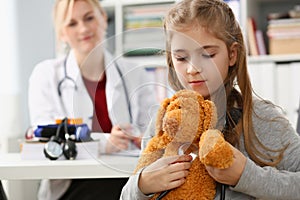 Little girl child holding toy and stethoscope at reception of pediatrician